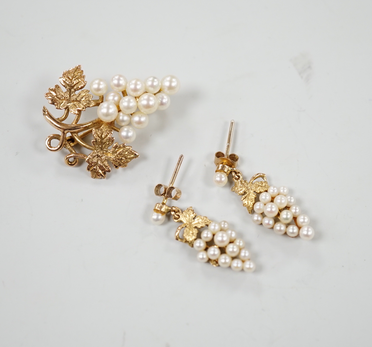 A modern 9ct gold and cultured pearl cluster set suite of jewellery, modelled as a bunch of grapes, comprising a brooch and pair of earrings, gross weight 7.3 grams.